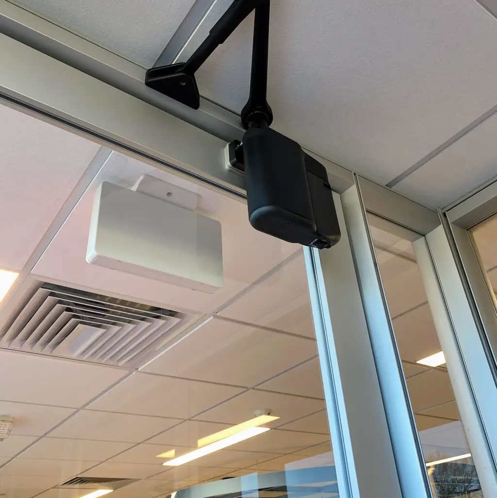 A commercial door closer fitted above a storefront door
